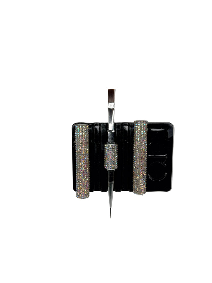 Dual-ended builder gel brush with crystal embellishments stay on top of black rectangular object with a white background 