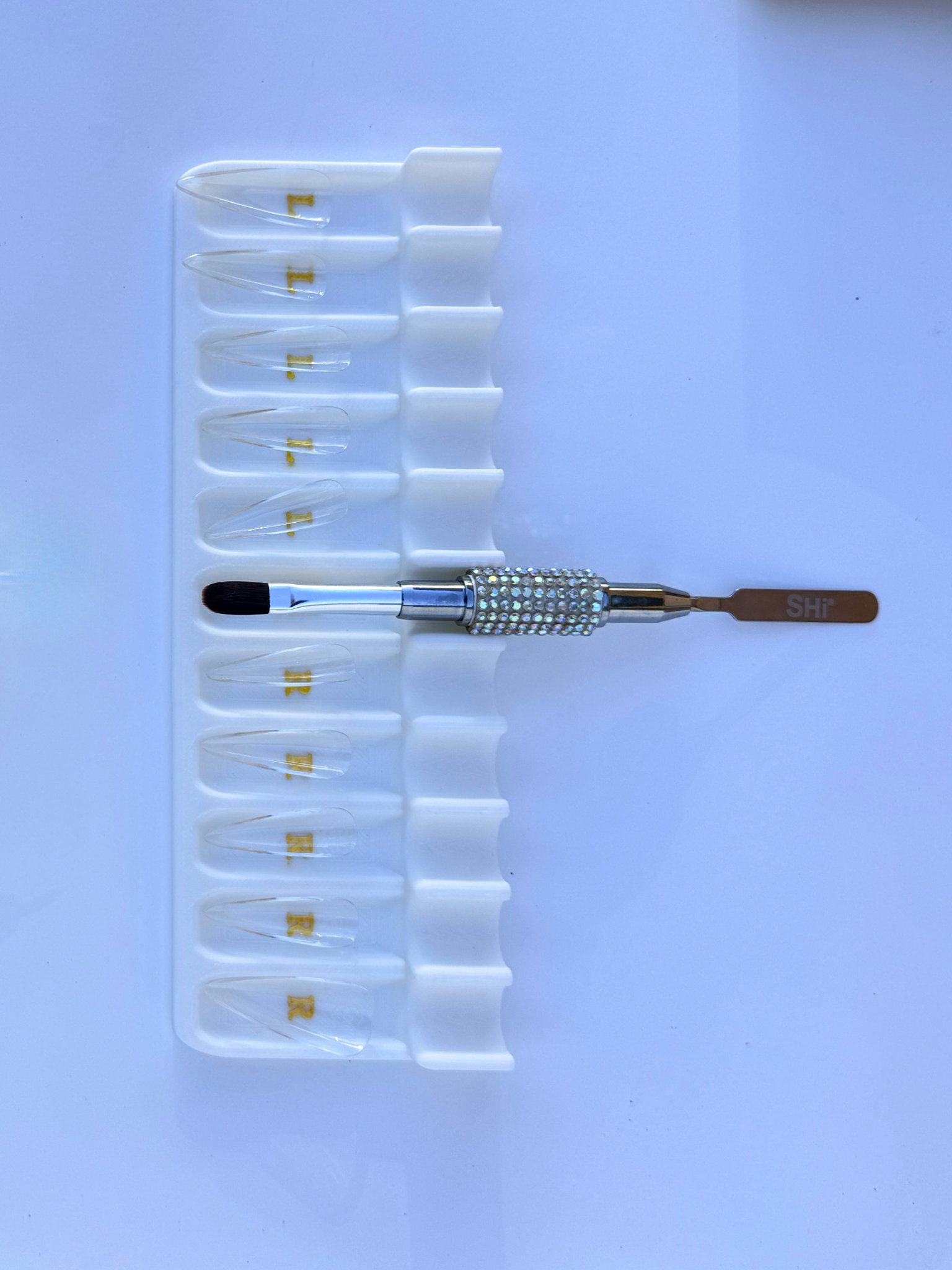 Set of clear soft gel tips, white tray, and bling brush with SHi brand logo on a white background