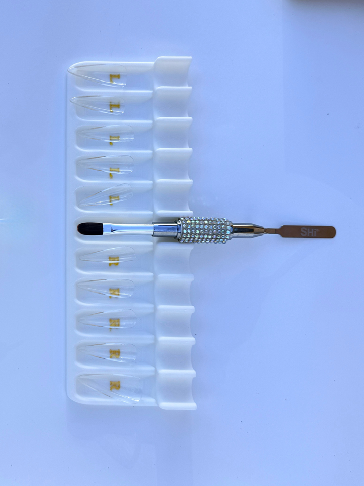 Set of clear soft gel tips, white tray, and bling brush with SHi brand logo on a white background