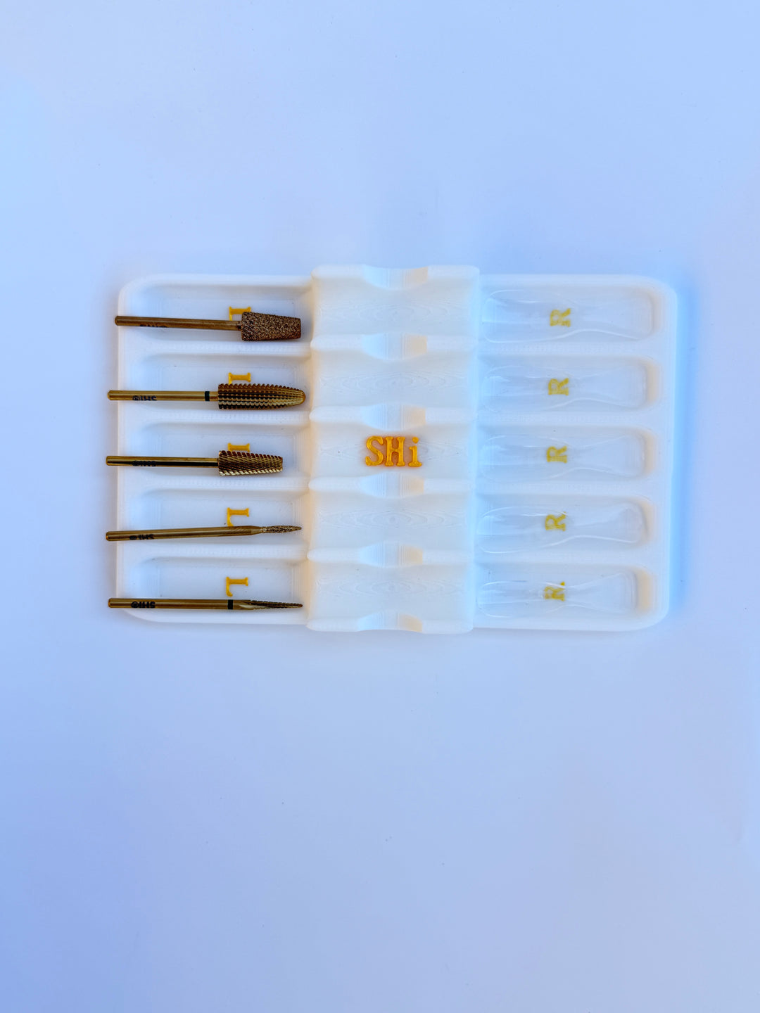 Set of nail drill bit in a white plastic case on a white background
