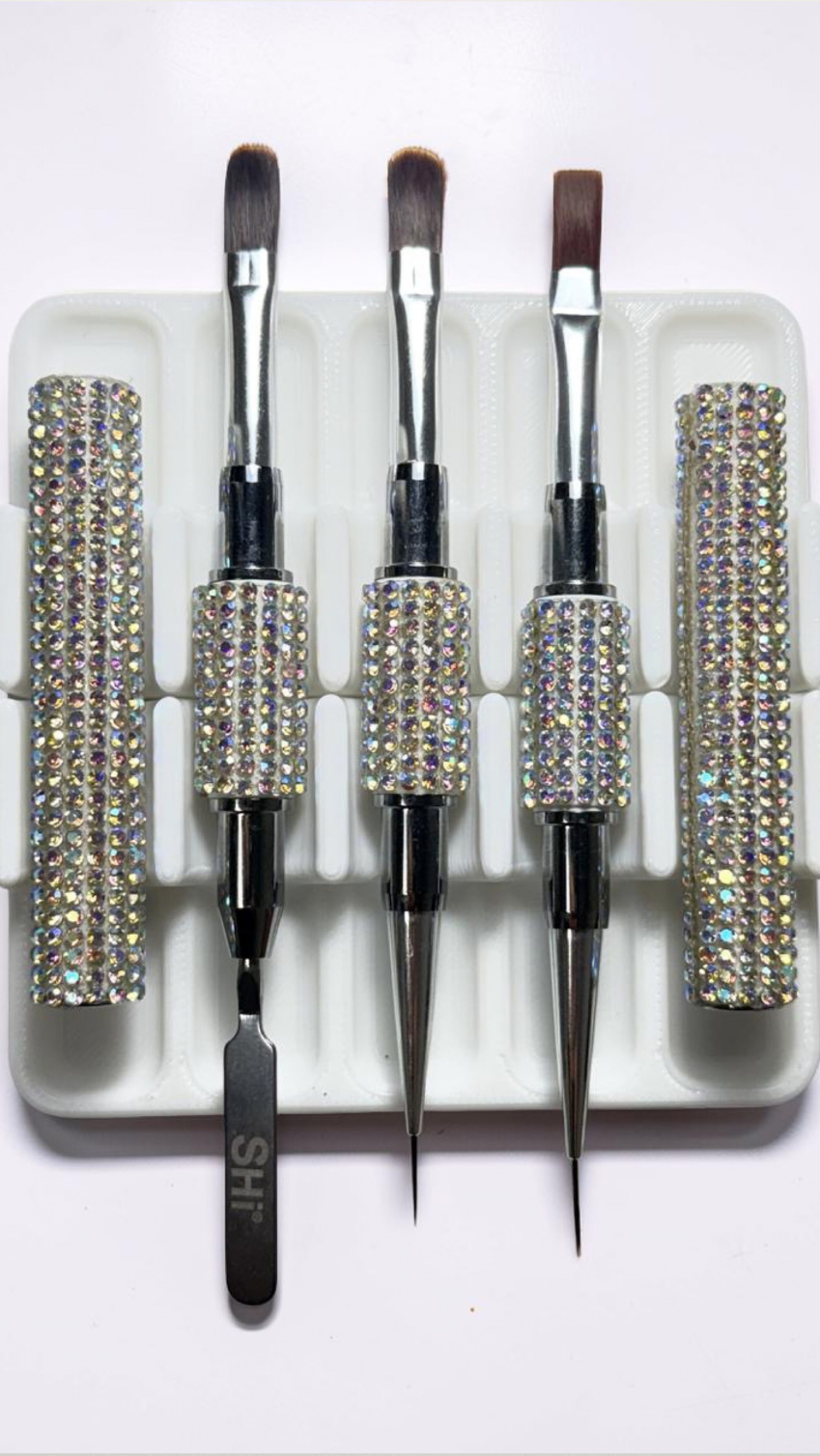 Set of 3 gel brushes with a decorative rhinestone case on a white background, surrounded by beauty products.