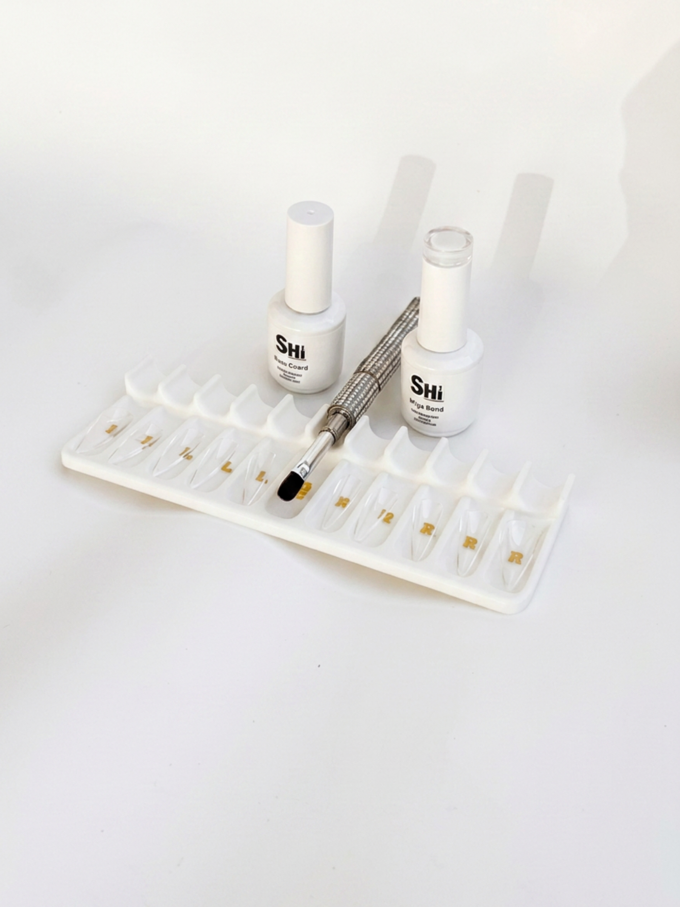 Two bottles of 'Shi' gel nail polish with a bling buillder gel brush and tray on a white background